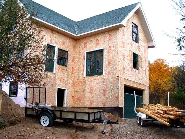 the same two story house before siding, with the bare OSB faces of the SIP panels showing