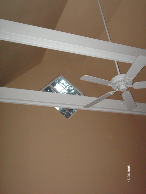 open cathedral ceiling with white collar ties, a ceiling fan and a diamond window in the gable