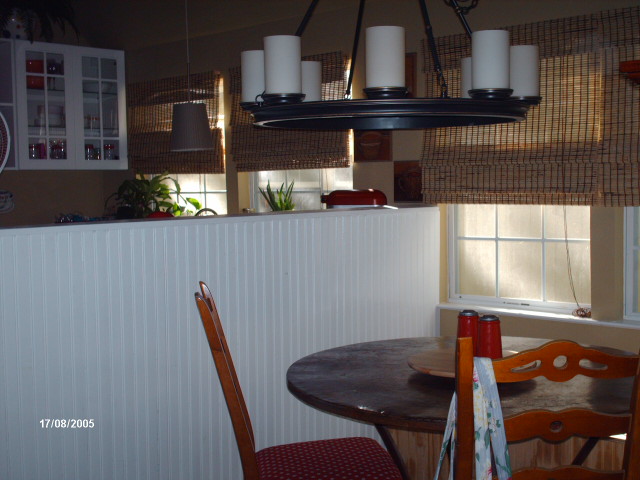 dining area with a round table and a candle chandelier beside the half wall to the kitchen