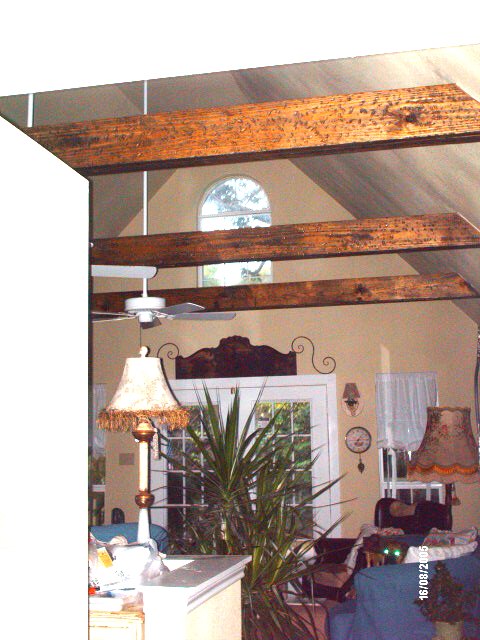 great room cathedral ceiling with dark exposed beams and an arched window in the gable