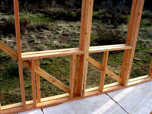 staggered double 2x4 wall framing at a corner of the cabin, seen through the open studs