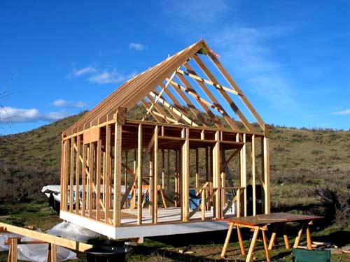 the cabin framed up with steep pitched rafters set, seen from the gable end