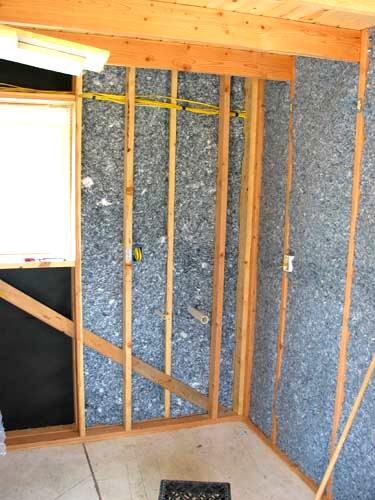 interior wall cavities packed with grey cotton denim batt insulation and wiring run through the studs