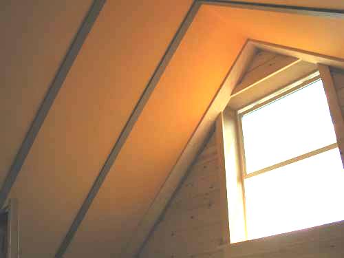 finished loft ceiling in strawboard panels with a bright gable window and pine boards below