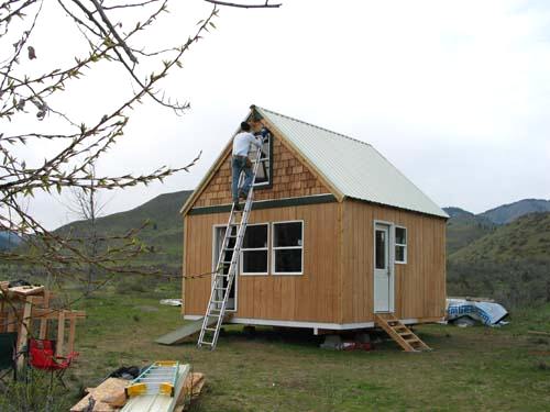 cedar shingles going up on the gable end from a ladder, with the siding and metal roof already on