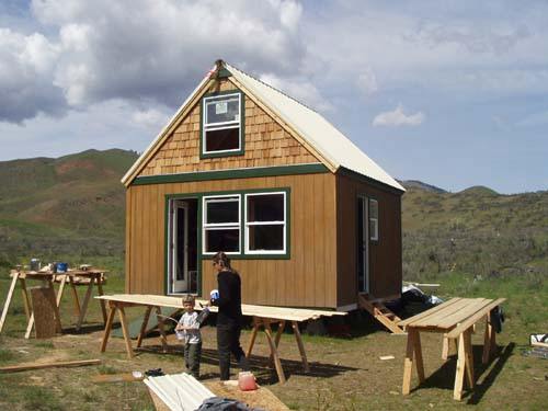 the finished 16x16 cabin with a cedar shingled gable, board siding and a light metal roof
