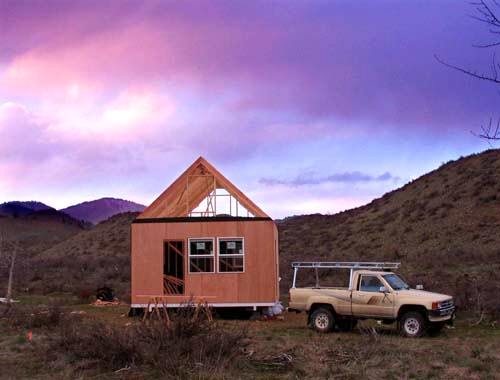 the sided cabin at sunset under a purple sky with the pickup truck parked alongside