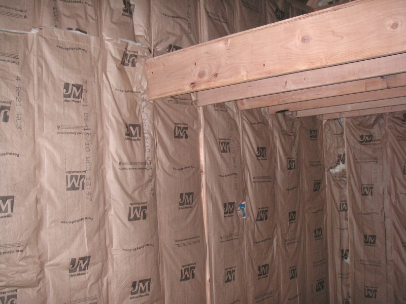 shop wall filled with kraft faced fiberglass batts between the studs, under the loft beam