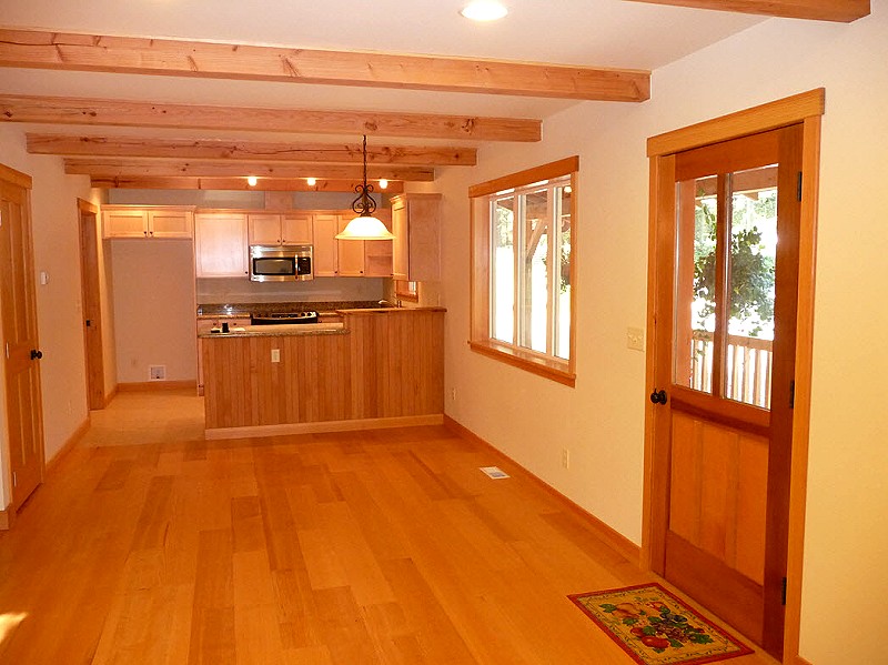 entry area with exposed ceiling beams, looking across the dining space to the kitchen