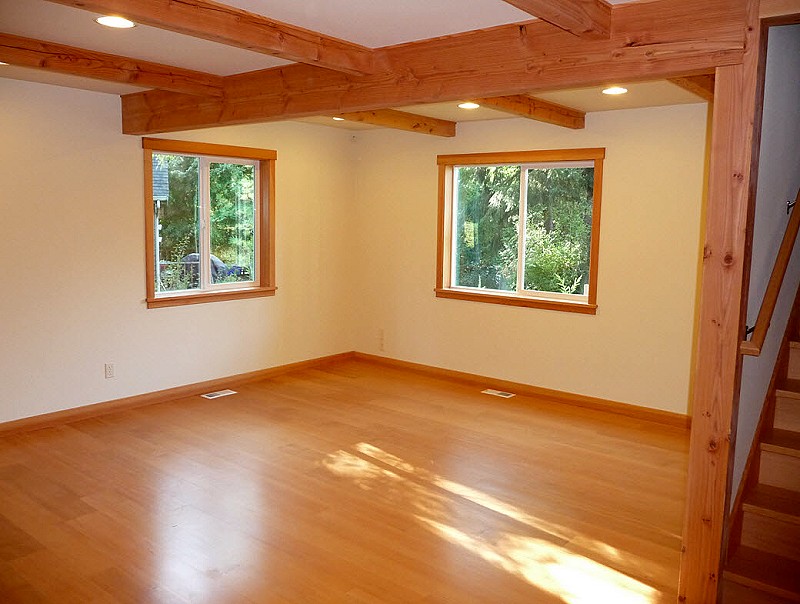 living room with exposed ceiling beams, two windows and a wood floor
