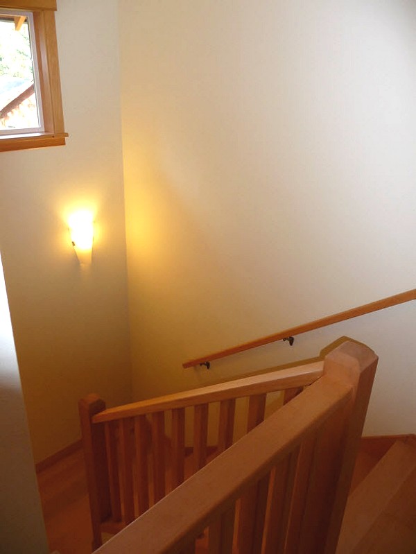 top of the stairway with a wood railing and a wall light