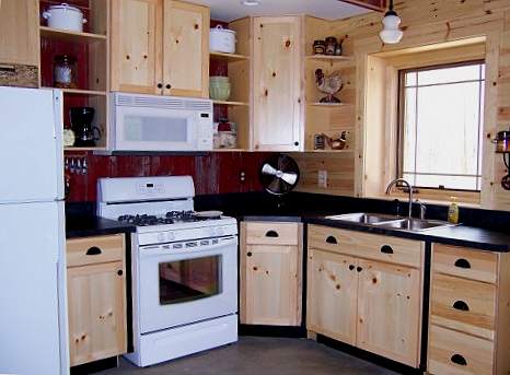 kitchen with knotty pine cabinets, black counters and a red barn wood wall behind the range