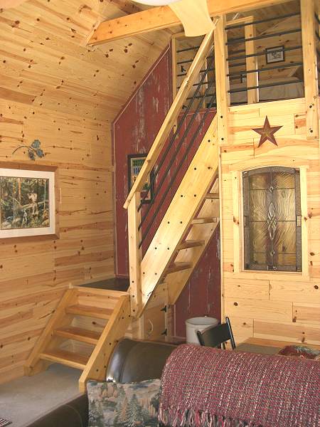 open stair climbing to the loft against a red barn wood wall, with a slim open railing