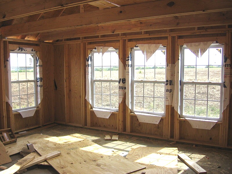 four windows installed, seen from inside, with the Tyvek cut back around the openings