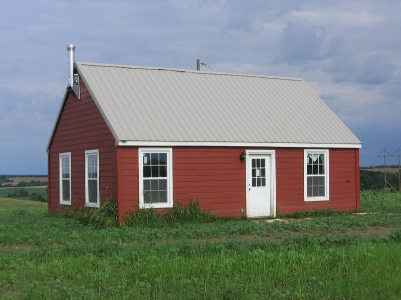 the finished 20x30 cottage painted red, with a metal roof and a chimney on the gable end