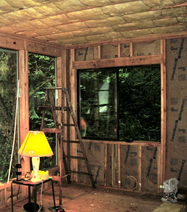 the inside of the office with batt insulation in the walls and ceiling and two big windows