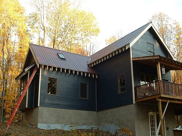 finished siding and metal roof over the main floor bedroom addition, seen from the yard below