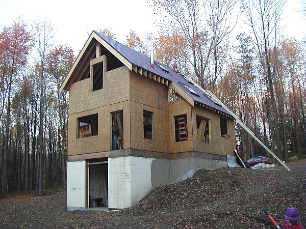 sheathed two story shell standing on the ICF basement, with the walkout opening on the downhill side