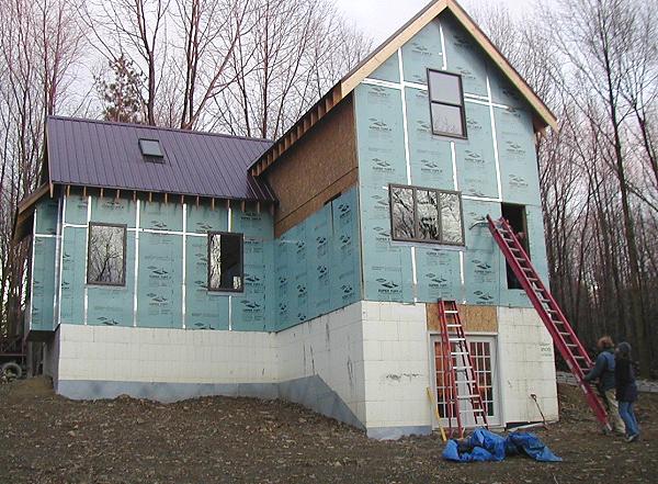 exterior insulation in place: taped foil faced board over the wall sheathing, above the white ICF basement wall