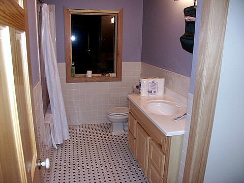 bathroom with tile wainscot, a hex tile floor and a wood framed window over the tub