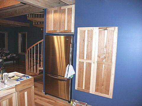 storage wall beside the refrigerator, with a matching hickory cabinet face built above it