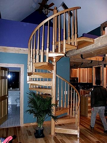 oak spiral stair winding up to the loft, with the kitchen behind it