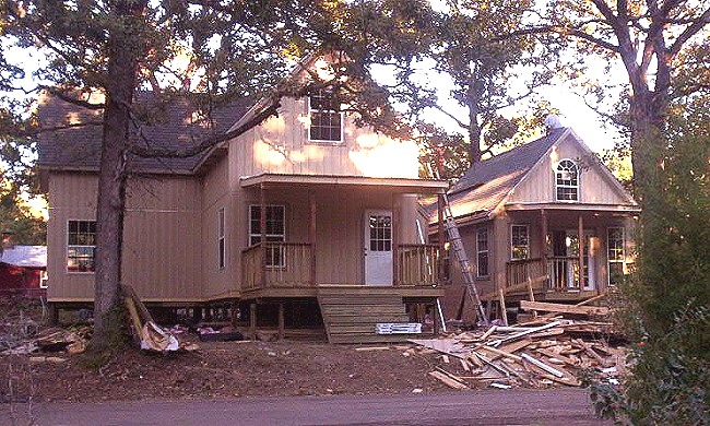 street view of the two cottages under construction among the trees