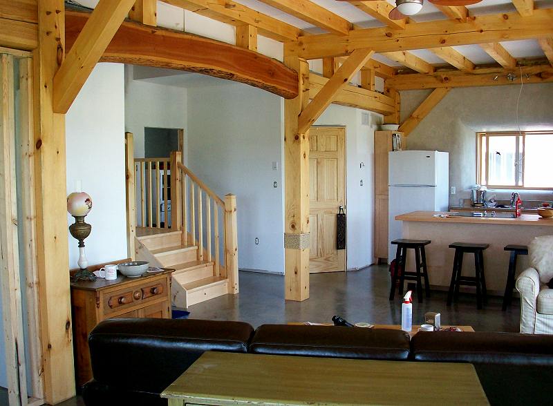 view from the living room past the stair to the kitchen and eating bar under exposed timber beams