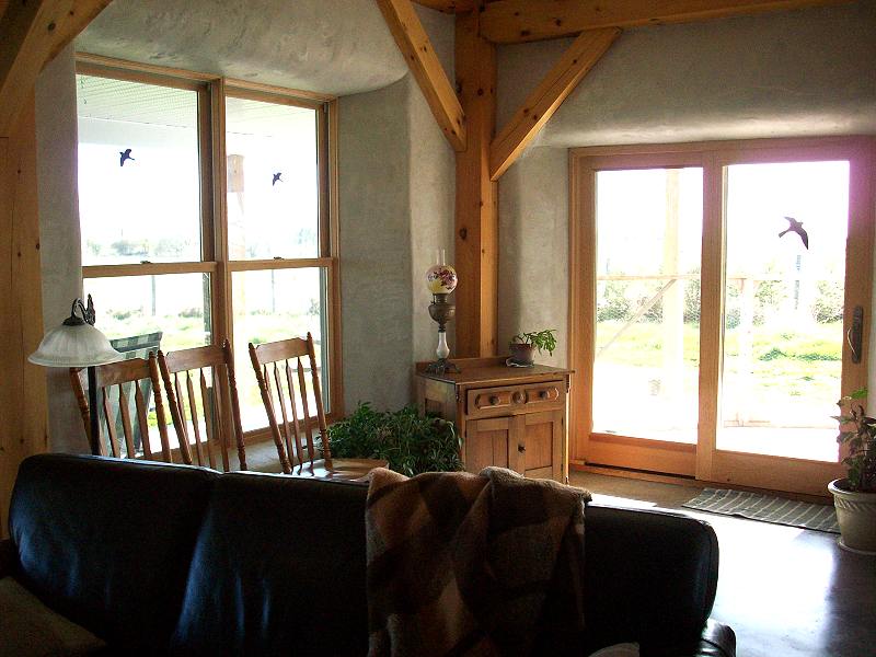 southwest corner of the living room with braced timber posts, deep plastered window wells and patio doors