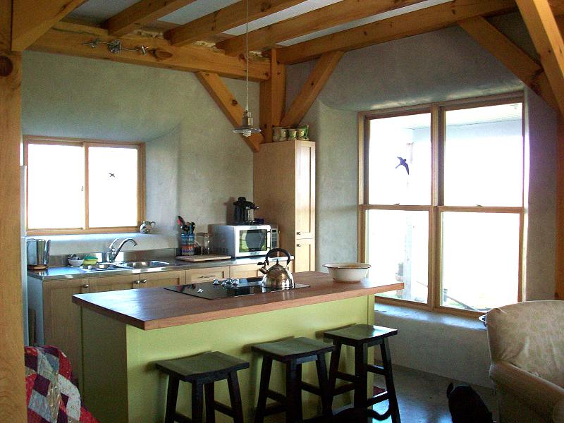 kitchen with a green island, cooktop and tall south facing windows set in deep plastered wells