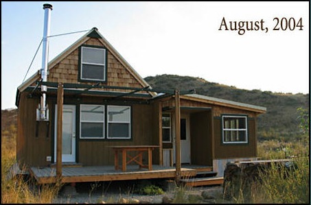the same cabin in August 2004 with a shed roof addition and a covered porch along the side