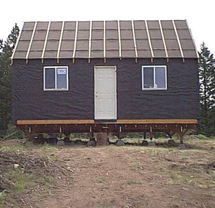 front of the 14x24 cabin wrapped in building felt with the door and two windows in place