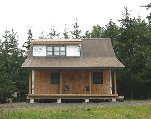 exterior of 16x24 cabin with metal roof and round concrete post footings