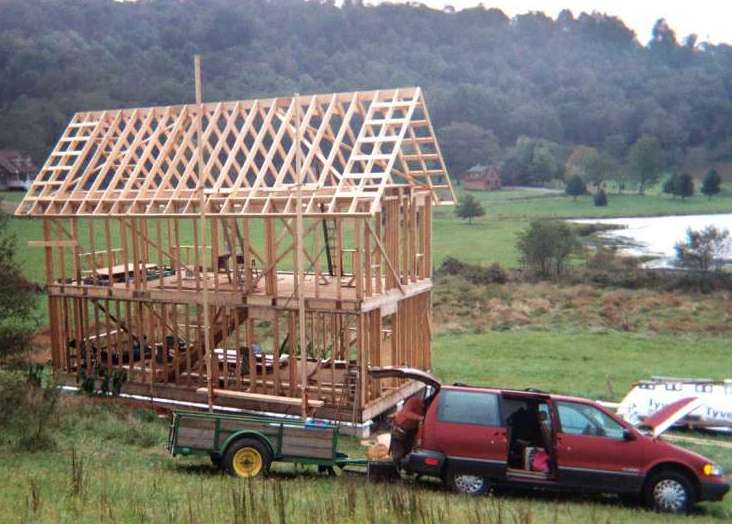 the two story frame and roof rafters standing open on the hillside above a pond