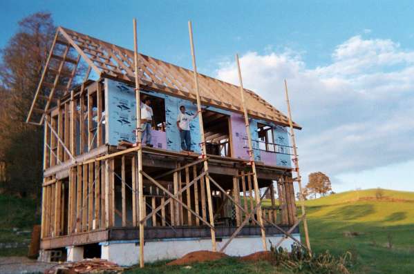 foam sheathing going on over the two by six walls, with scaffolding around the house and the porch framing in place