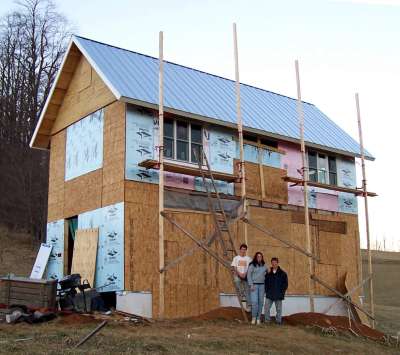 the house with its galvanized metal roof on and structural sheathing part way up the gable end