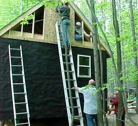 two men on ladders finishing the sheathing at the open gable end