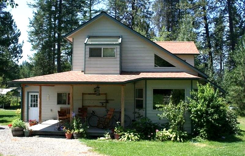 side of the house showing the full saltbox roof slope, the clerestory window band above the porch roof and the porch wrapping the corner
