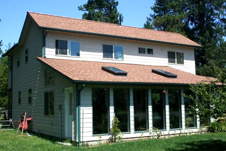 glazed sunroom running along the ground floor of the house, with two skylights in the shed roof above it