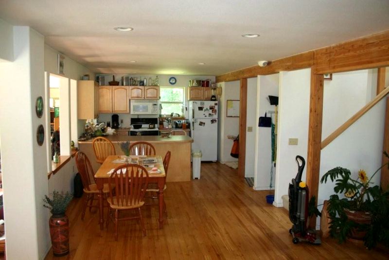 kitchen and dining area on a wood floor, with an eating bar, a pass through to the sunroom on the left and the stair on the right
