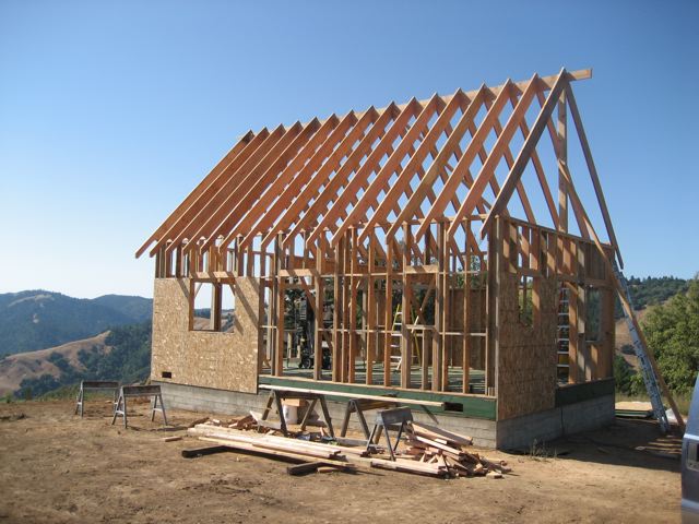 the 1-1/2 story frame with walls up and rafters set, on the open mountain site