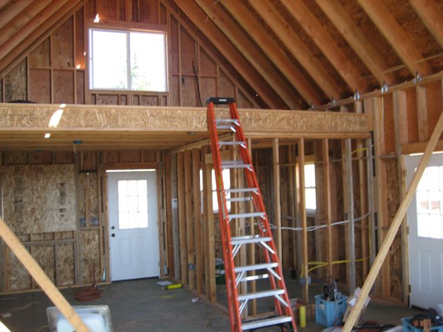 inside the shell with the loft floor framed and decked, front door already hung