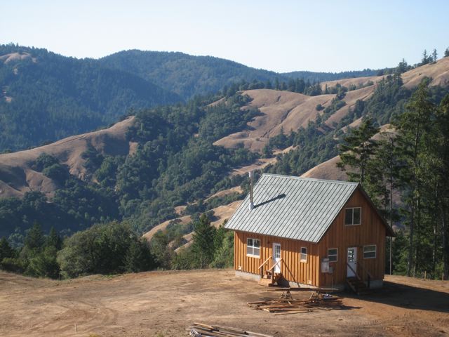 the finished cottage under its metal roof on the ridge, above the Mendocino hills