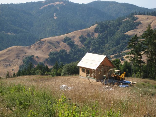 the 20x30 cottage framed and roof sheathed in a dry meadow, with the Mendocino hills behind